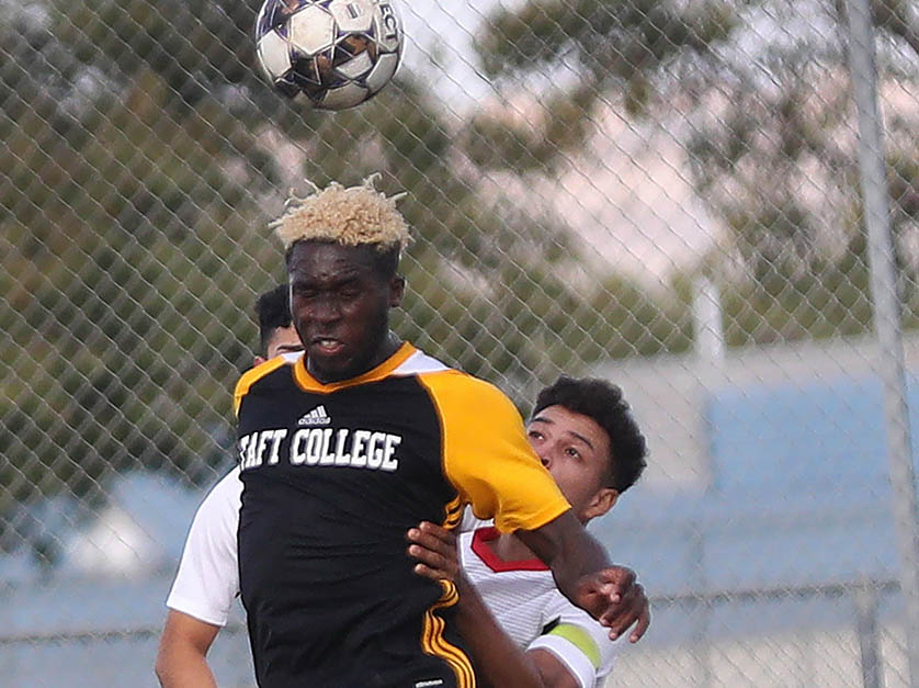 Two Men's Soccer opponents vie for the ball, and it is headed into the air.